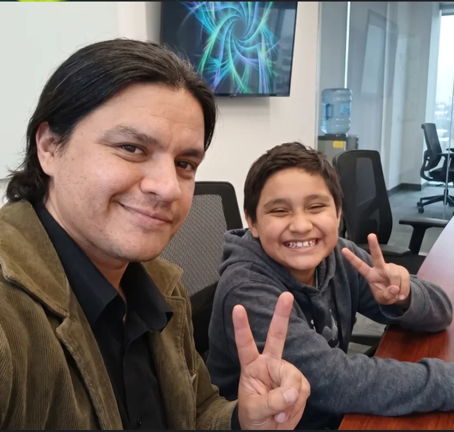 Raúl y un alumno en el salón, los dos haciendo la señal de paz